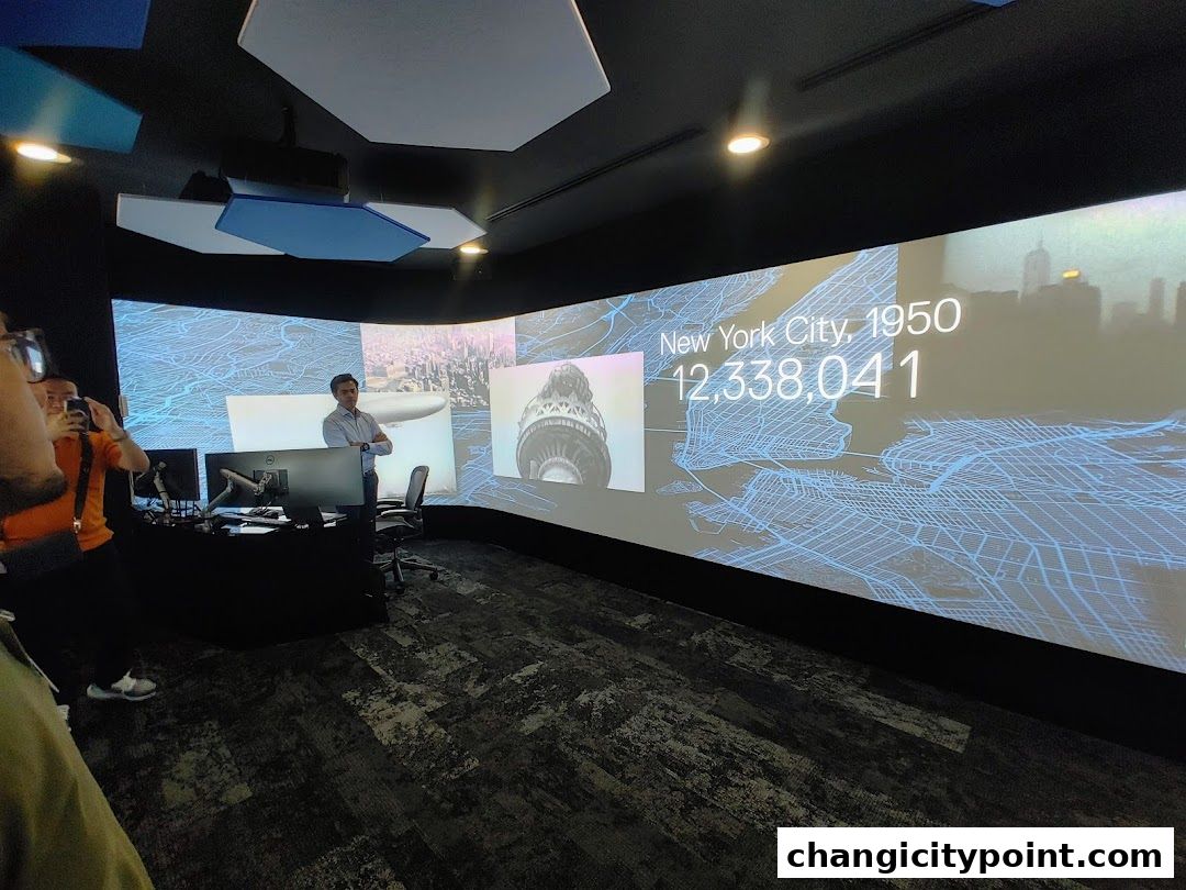 A man stands in front of a large curved screen displaying data about New York City.
