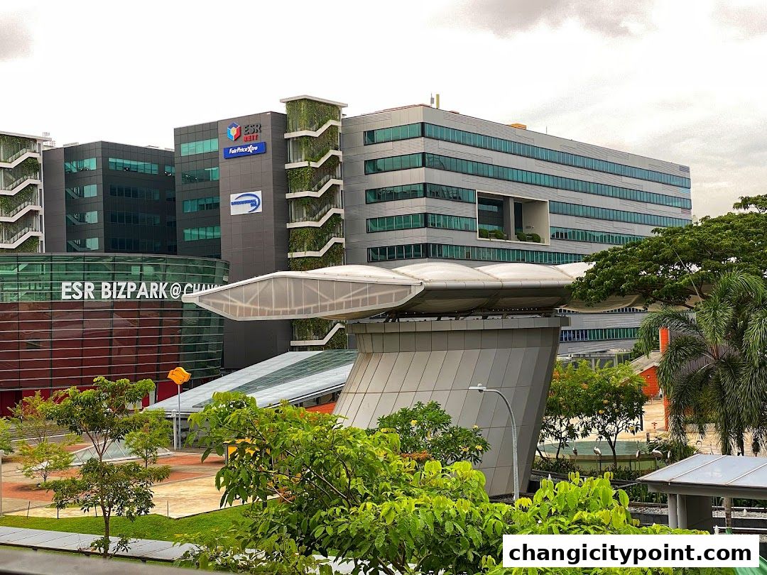 Modern office buildings with green spaces and a covered walkway.