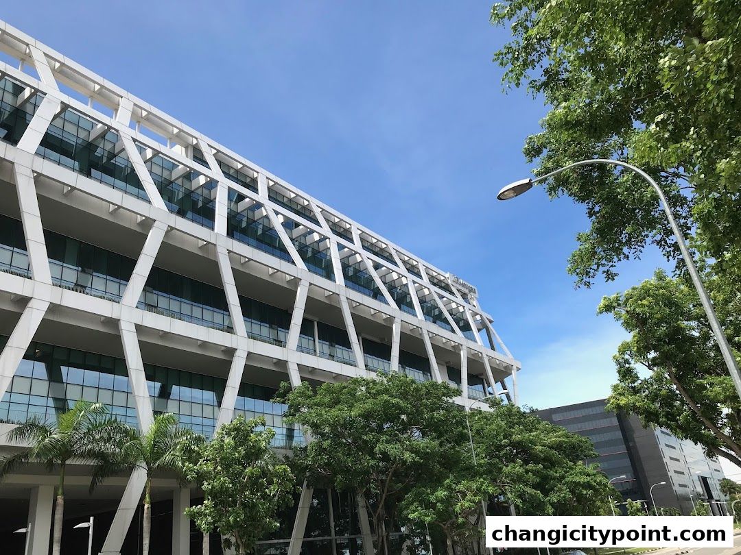 Modern office building with a distinctive geometric facade and lush green trees.