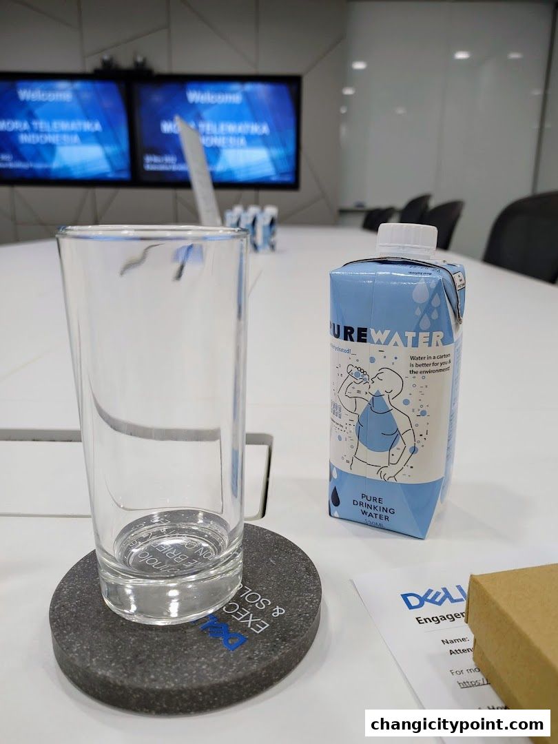 A glass and a carton of Pure Water sit on a table in a meeting room.