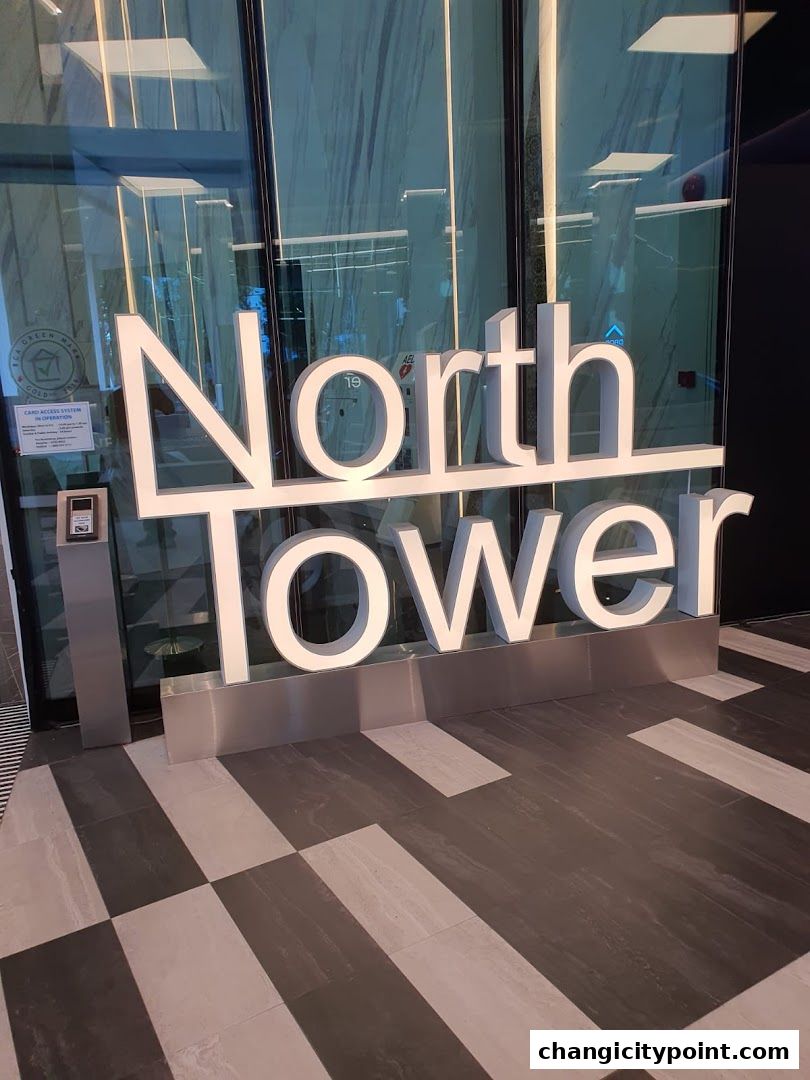 Large white 'North Tower' signage in front of a modern glass building entrance.