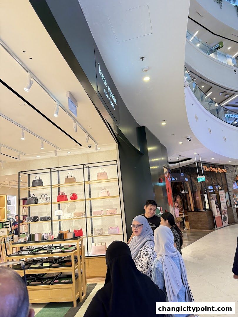 Kate Spade New York store interior with handbags displayed on shelves and customers browsing.