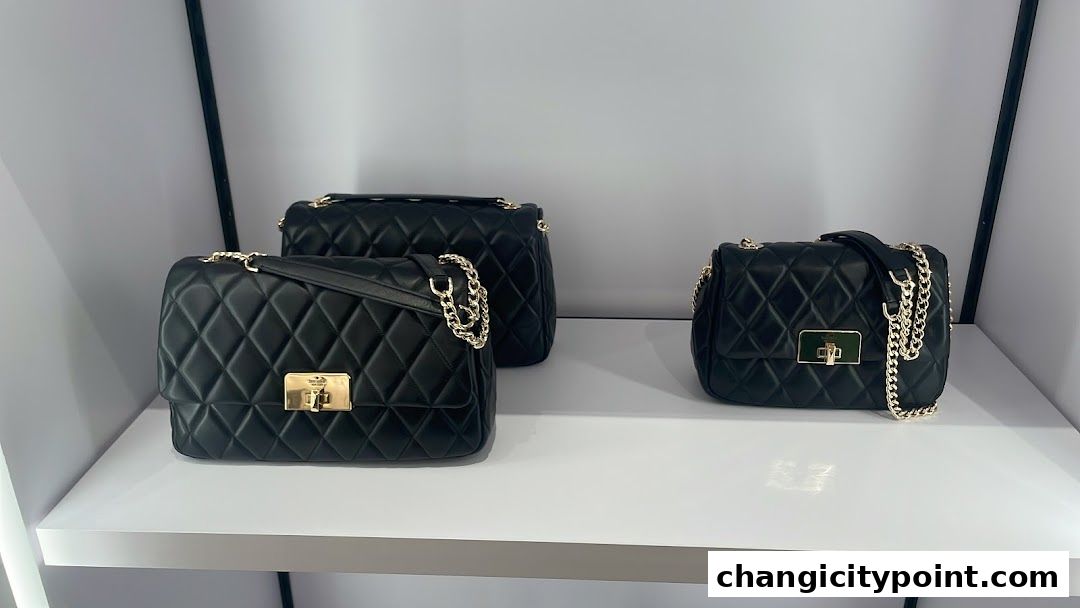 Three quilted black leather handbags with gold chain straps displayed on a white shelf.