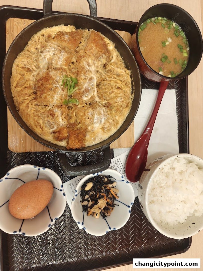 A delicious katsudon meal with rice, miso soup, and side dishes served on a tray.