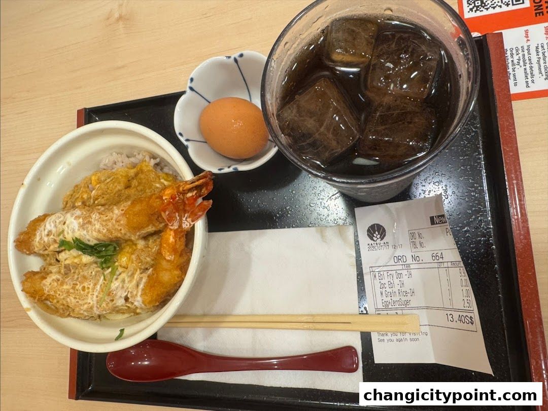 A delicious meal of shrimp katsu don, a boiled egg, and a drink on a tray.