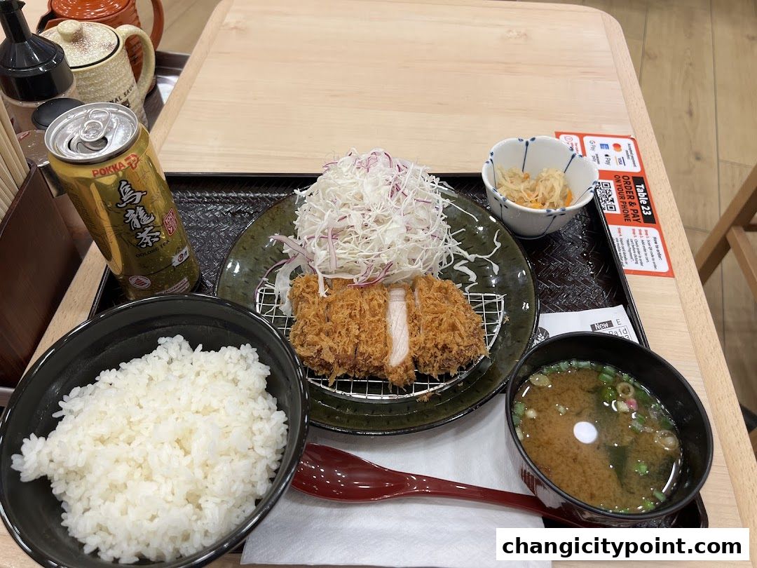 A delicious katsu set meal with rice, miso soup, and a canned oolong tea.
