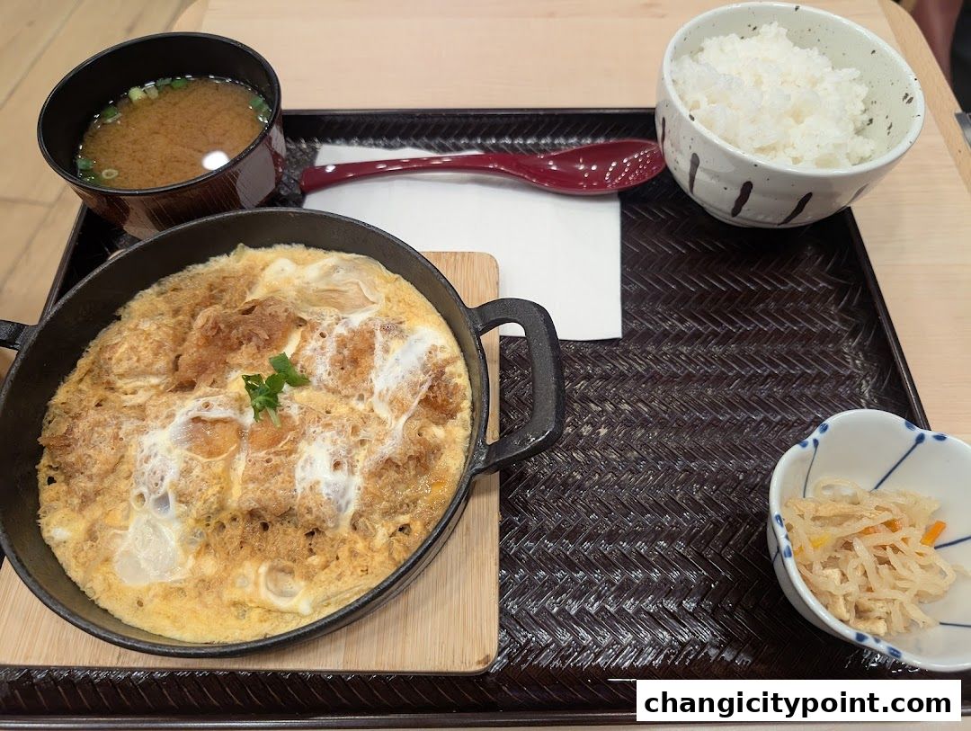 A delicious katsudon meal with rice, miso soup, and a side dish.