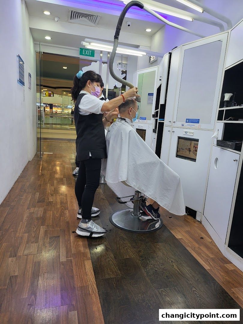 A hairstylist cuts a client's hair with a vacuum attachment in a modern salon.