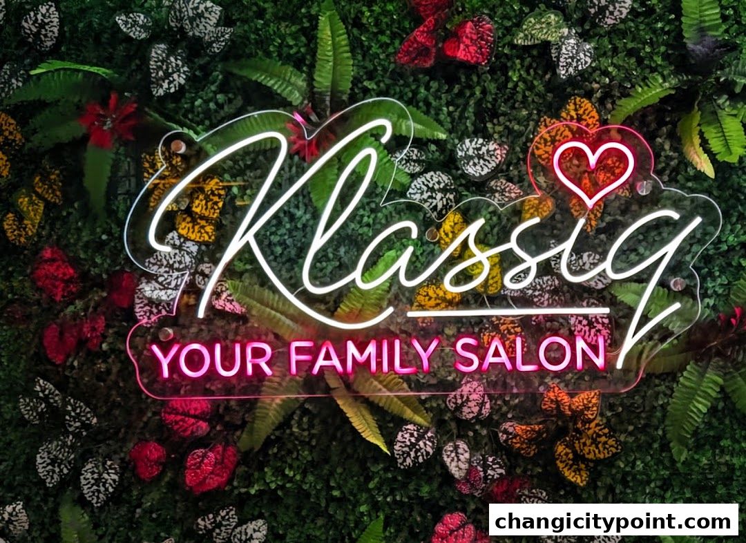 A neon sign for Klassiq Family Salon with a heart motif, set against a lush green backdrop.