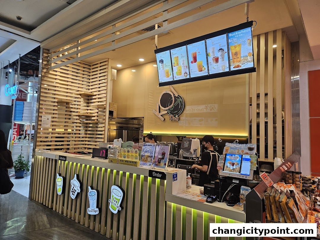 A KOI Express bubble tea shop counter with staff preparing drinks and a digital menu.