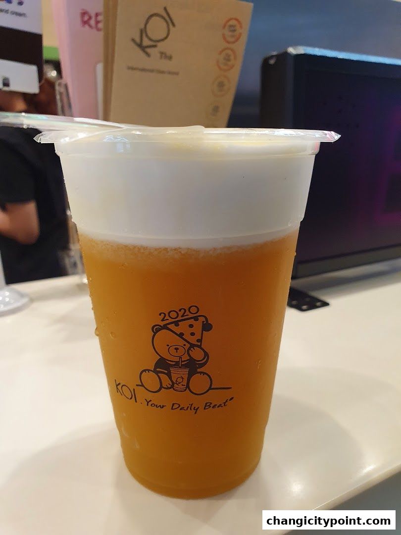 A refreshing KOI The drink with a creamy foam top and a cute bear logo.