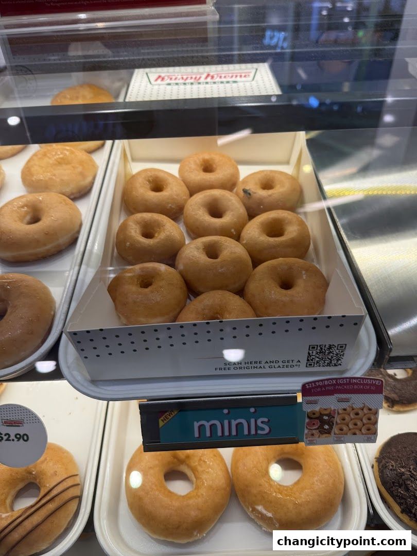 A display case filled with assorted Krispy Kreme donuts, including glazed and mini varieties.