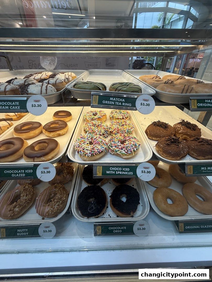 A display case filled with various Krispy Kreme donuts, including glazed, chocolate, and specialty flavors.