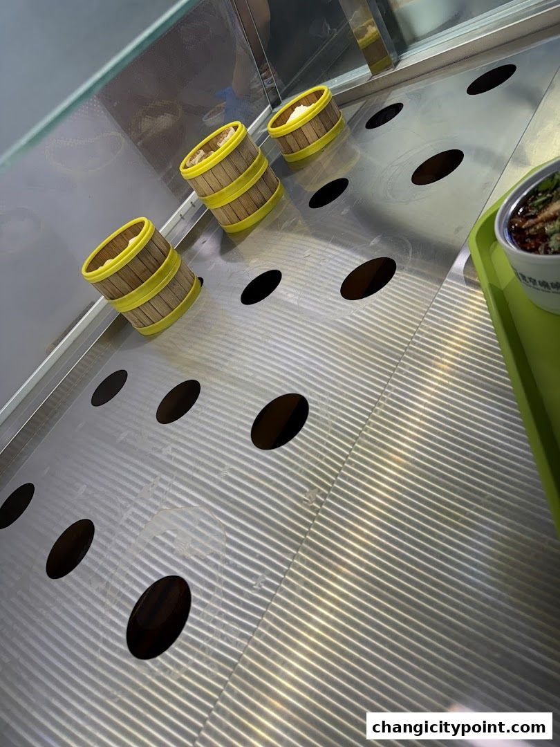 Steaming baskets filled with food are displayed on a metal surface with circular cutouts.