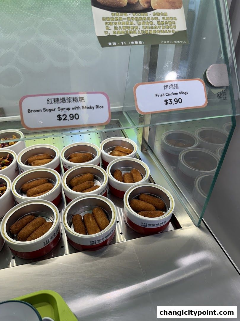 A display case showing fried snacks and chicken wings with prices.