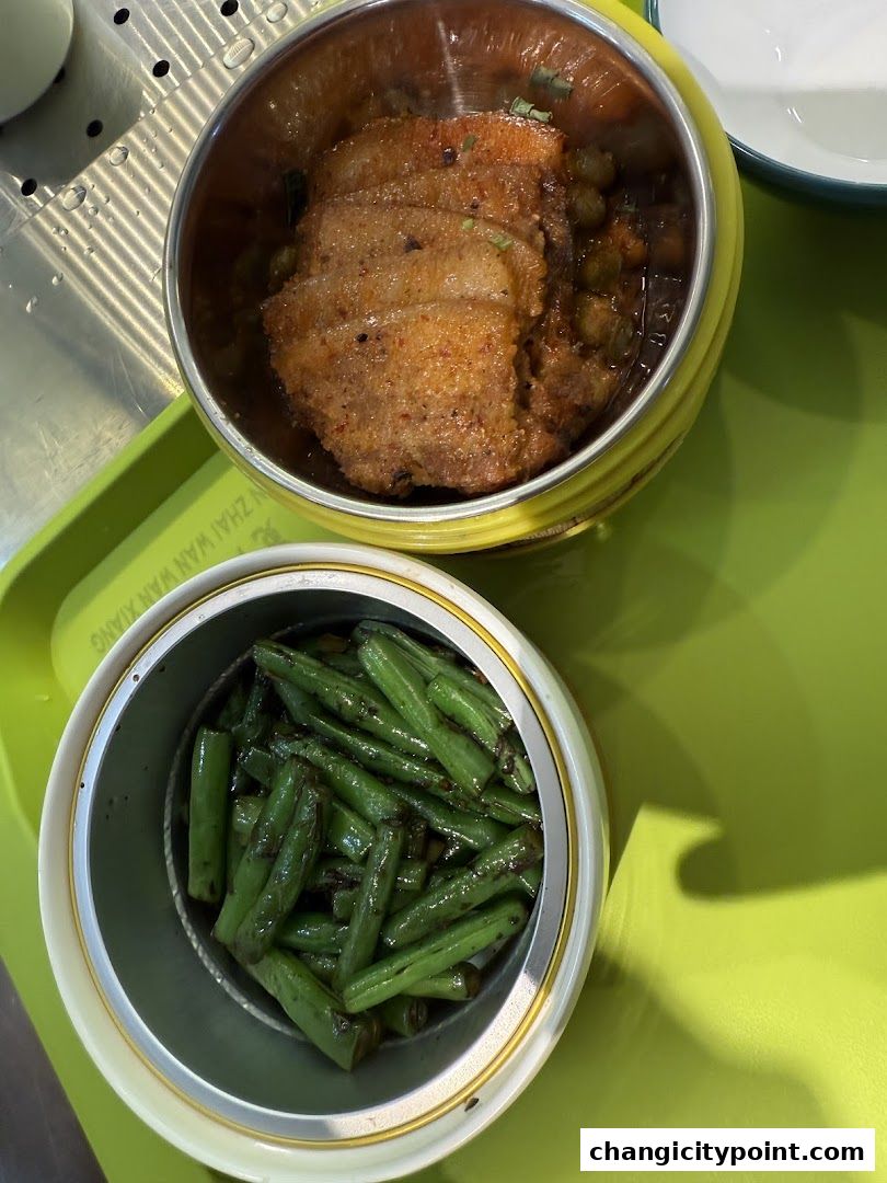 Two metal containers holding a meat dish and green beans on a green tray.