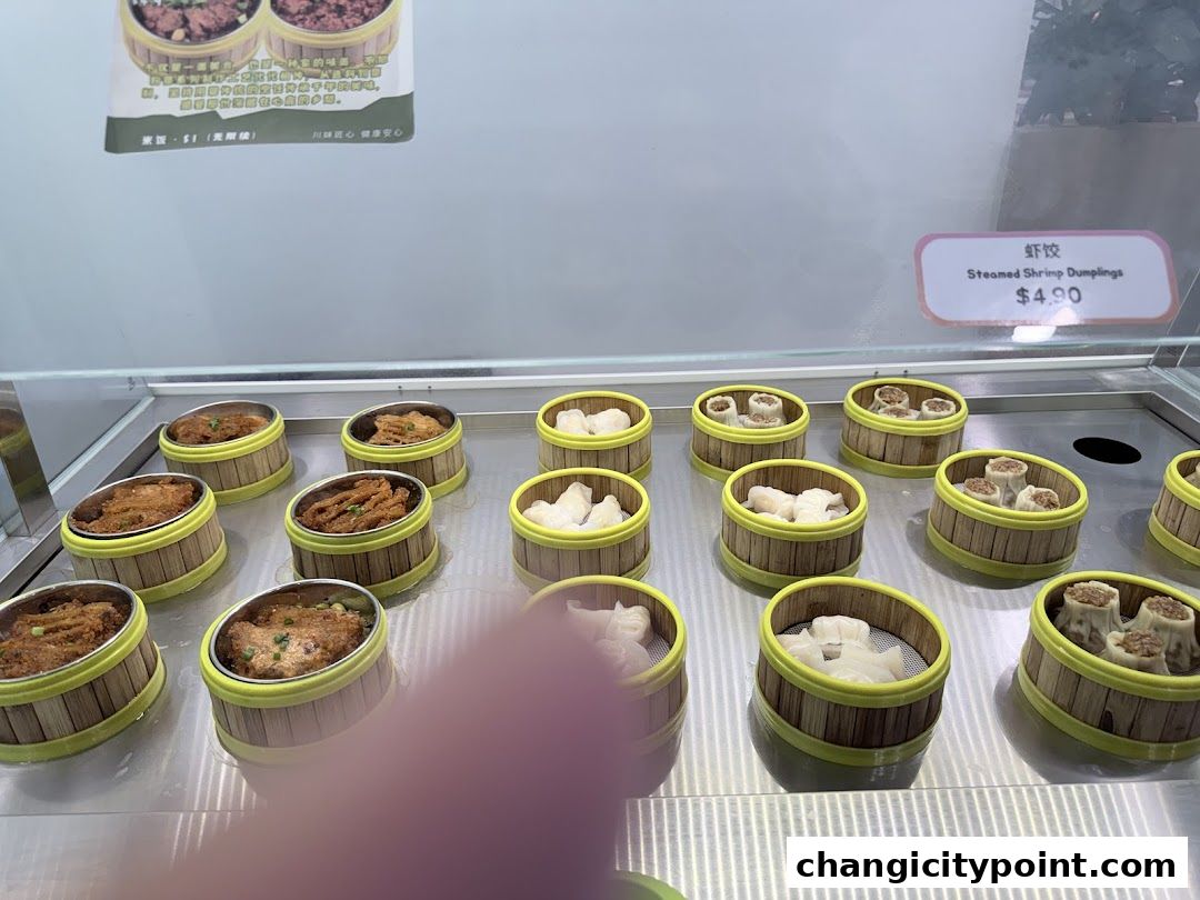 A display of various steamed dumplings in bamboo baskets at a food stall.