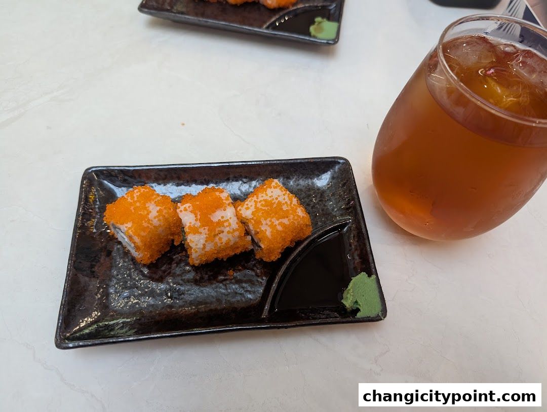 A plate of California rolls with wasabi and soy sauce, next to a glass of iced tea.