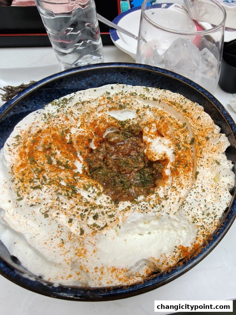 A close-up of a creamy dish topped with spices and herbs, served in a dark blue bowl.