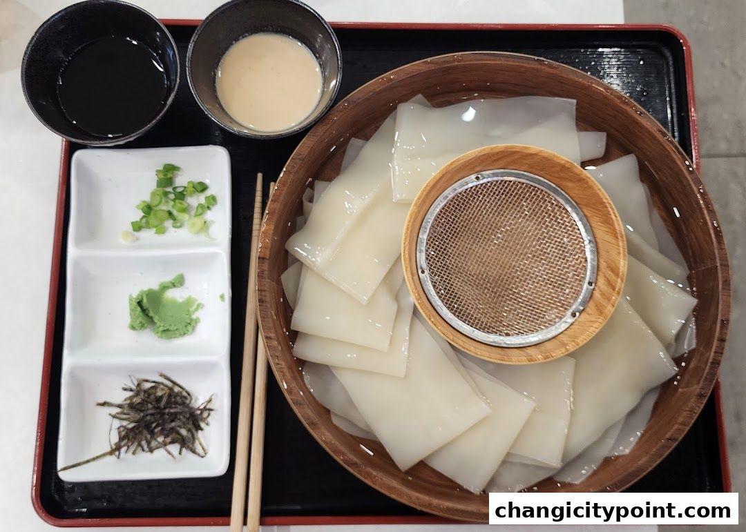 A close-up of a Japanese dish with noodles, dipping sauces, and condiments.