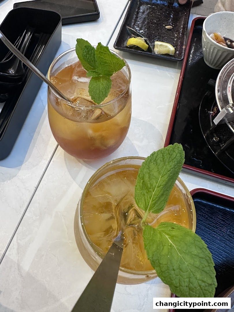 Two refreshing iced teas with mint garnishes on a tiled table.