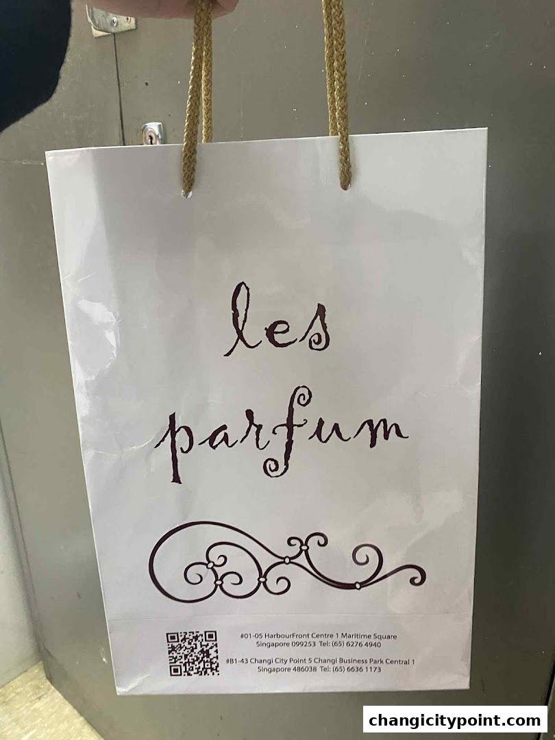 A white shopping bag with the 'Les Parfum' logo and store addresses.
