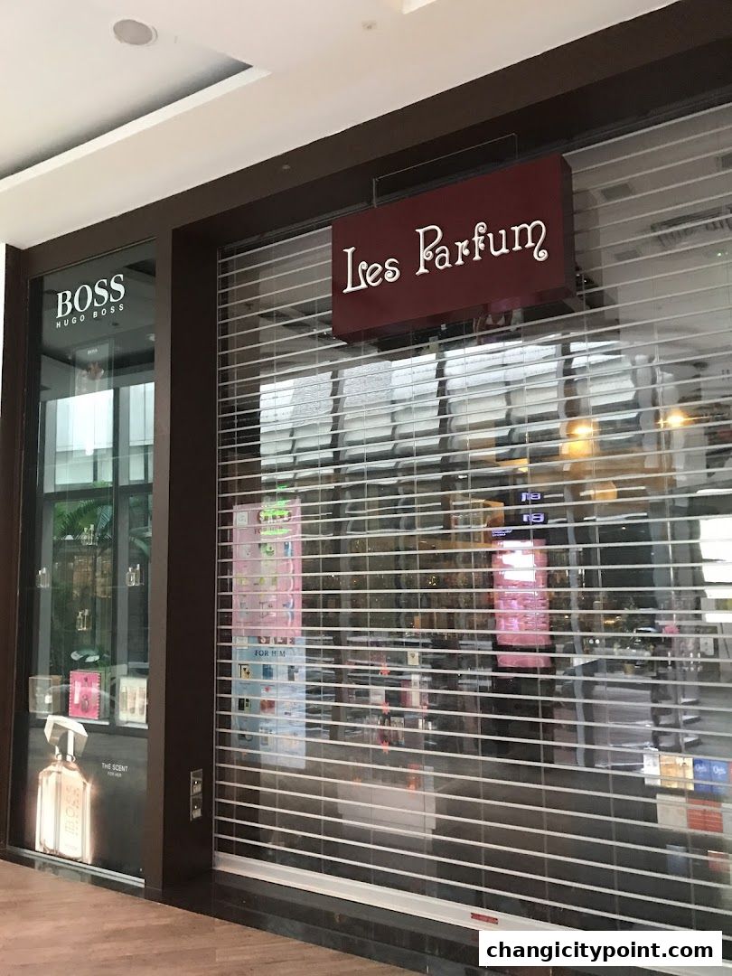 The storefront of Les Parfum, a perfume shop, with a closed security gate.
