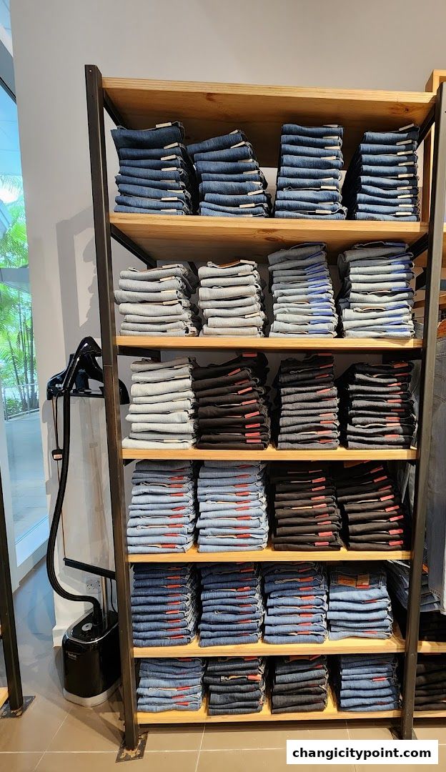 Neatly folded stacks of jeans in various washes and colors on display shelves.