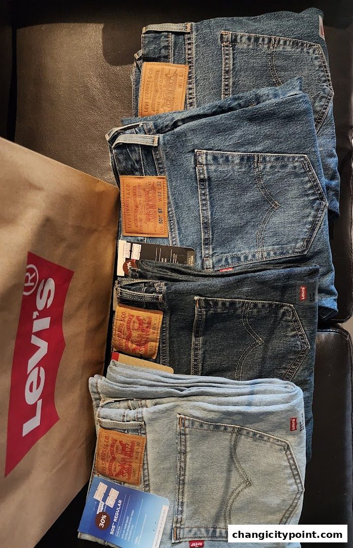 A collection of folded Levi's jeans and a shopping bag on a dark surface.
