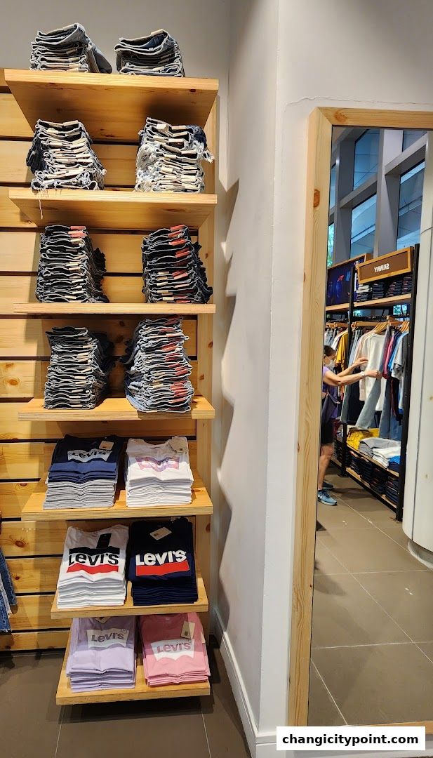 Neatly folded Levi's jeans and t-shirts displayed on wooden shelves inside a store.