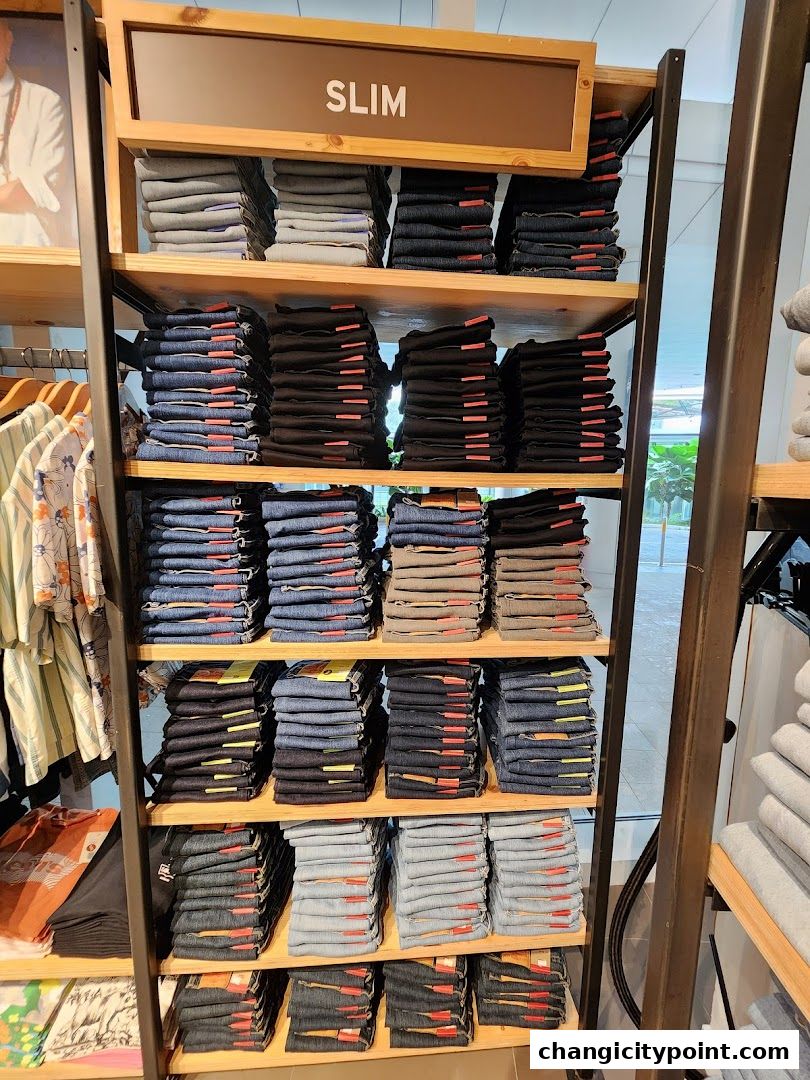 Neatly folded stacks of jeans in various washes and colors on display shelves.