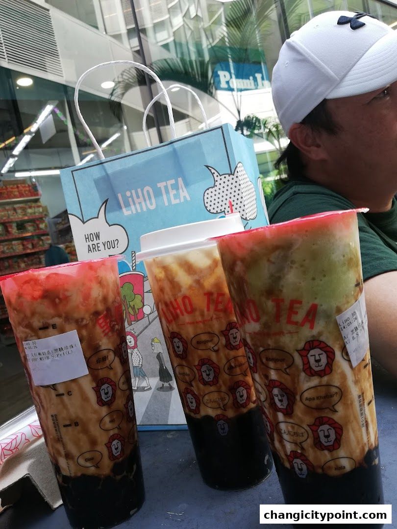 Three cups of LiHO TEA bubble tea with a shopping bag and a person in the background.