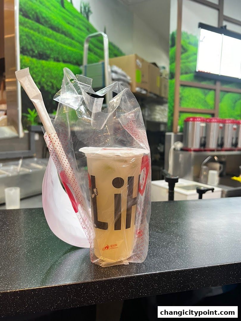 A LiHO TEA drink in a plastic bag with a straw on a counter.