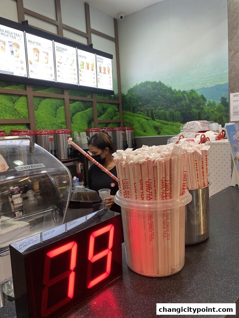 A LiHO TEA counter with a staff member, menu boards, and branded straws.
