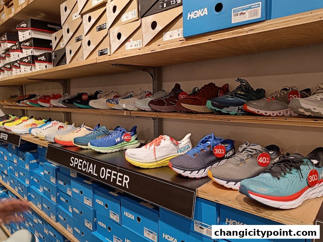 Shelves stocked with various athletic shoes and shoe boxes from brands like Hoka and Saucony.