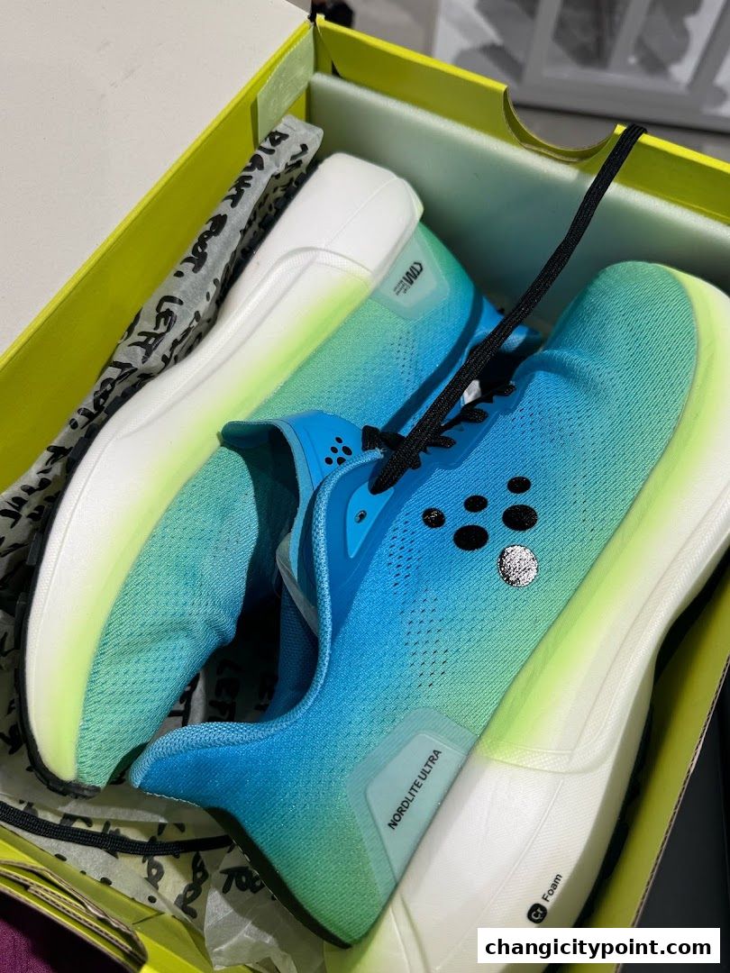 A pair of blue and green gradient running shoes in a yellow box.