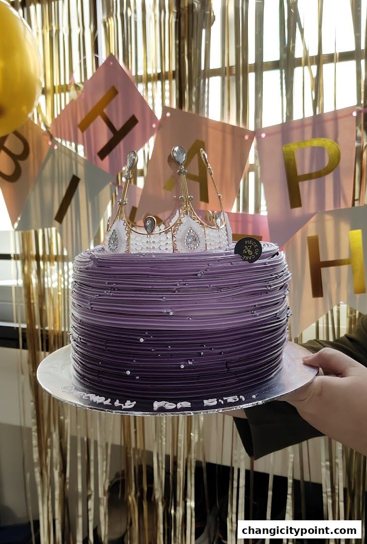 A purple ombre cake with a crown topper and 'Happy Birthday' banner.