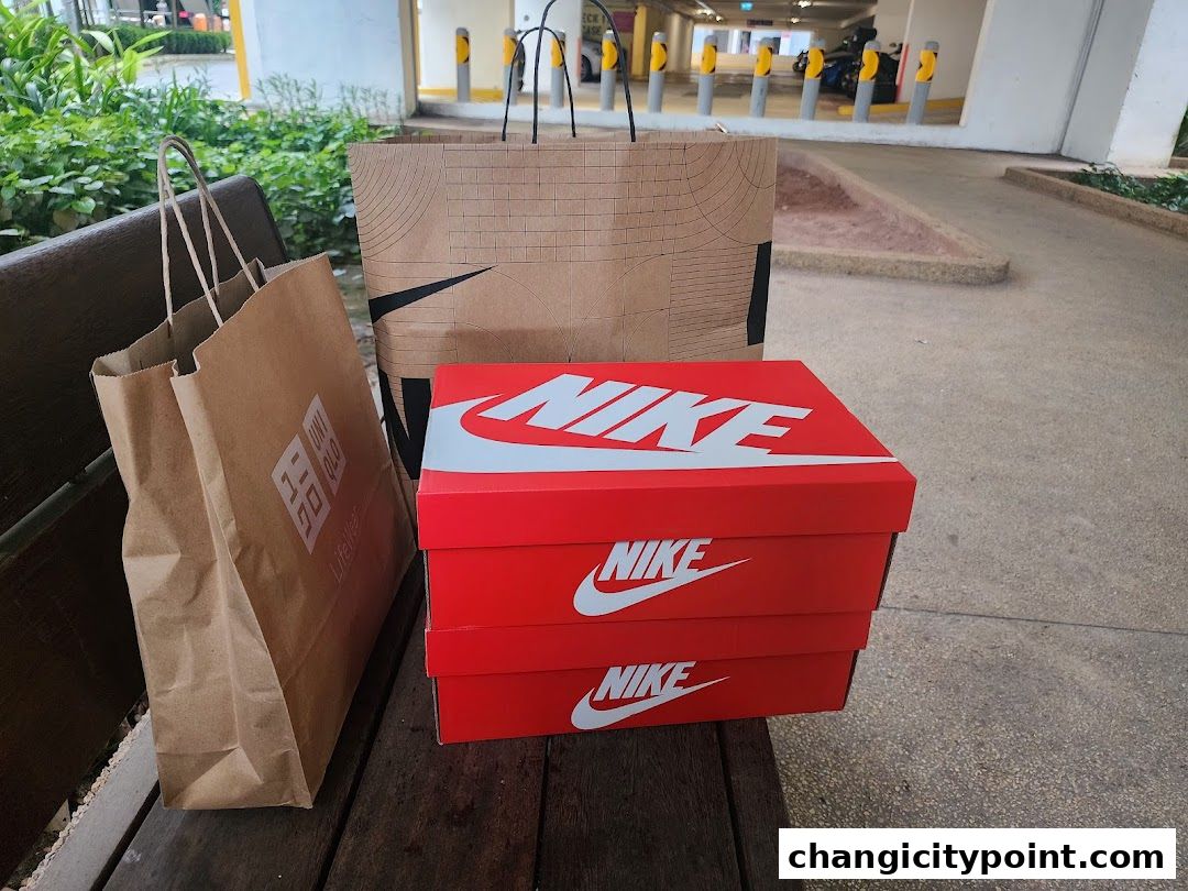Shopping bags from Uniqlo and Nike boxes stacked on a wooden bench.