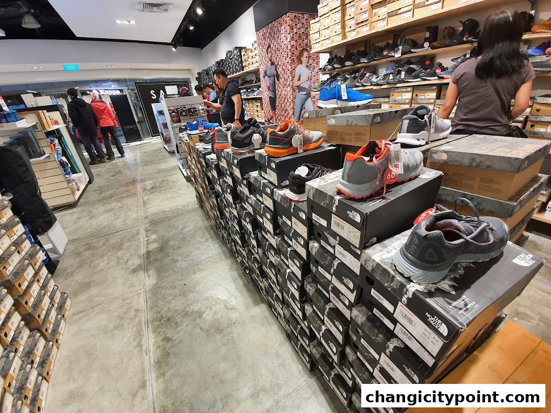 Interior view of a sports shoe store with shoes displayed on shelves and stacked boxes.