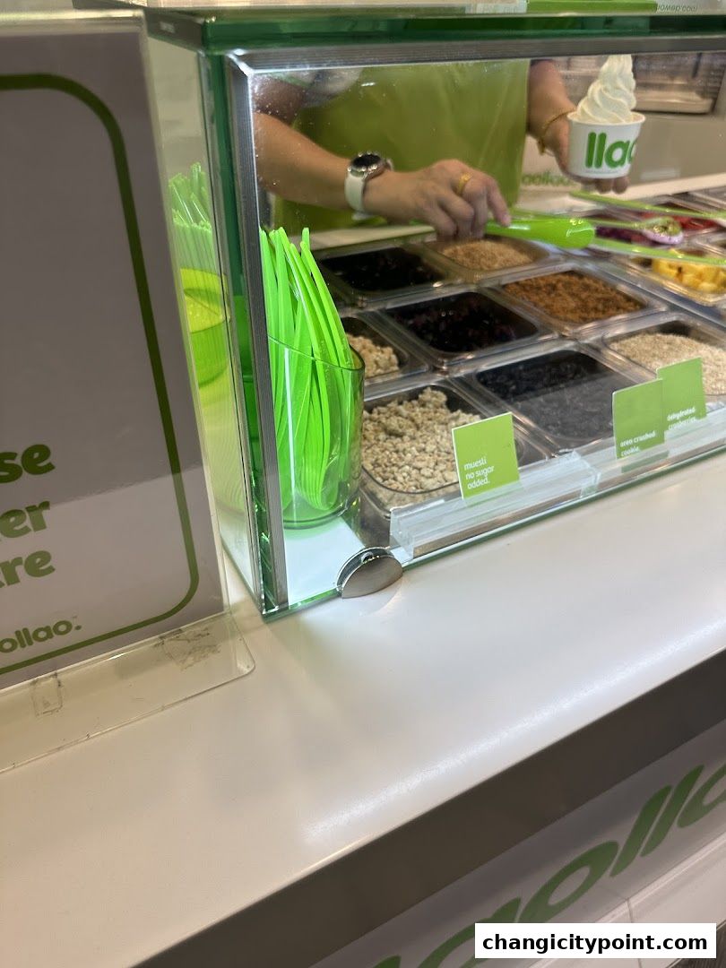 A person is serving frozen yogurt with various toppings at a llaollao shop.