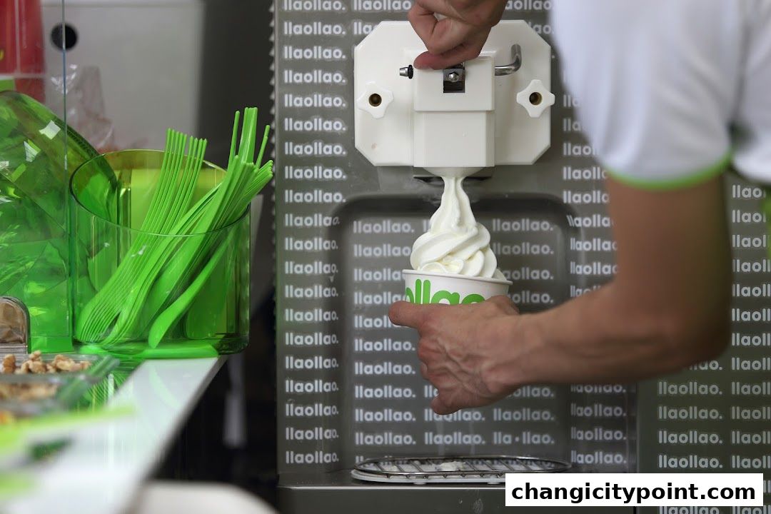 A hand dispenses frozen yogurt into a cup from a machine at llaollao.