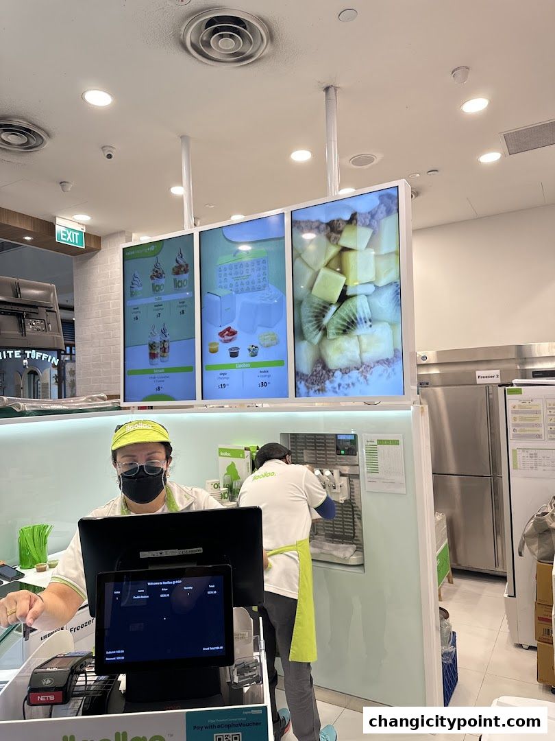 Staff members working at a llaollao frozen yogurt shop with digital menus and freezers.