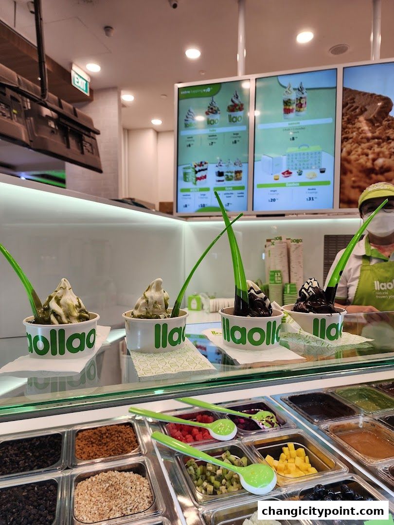 A display of llaollao frozen yogurt cups and a variety of toppings in a refrigerated case.