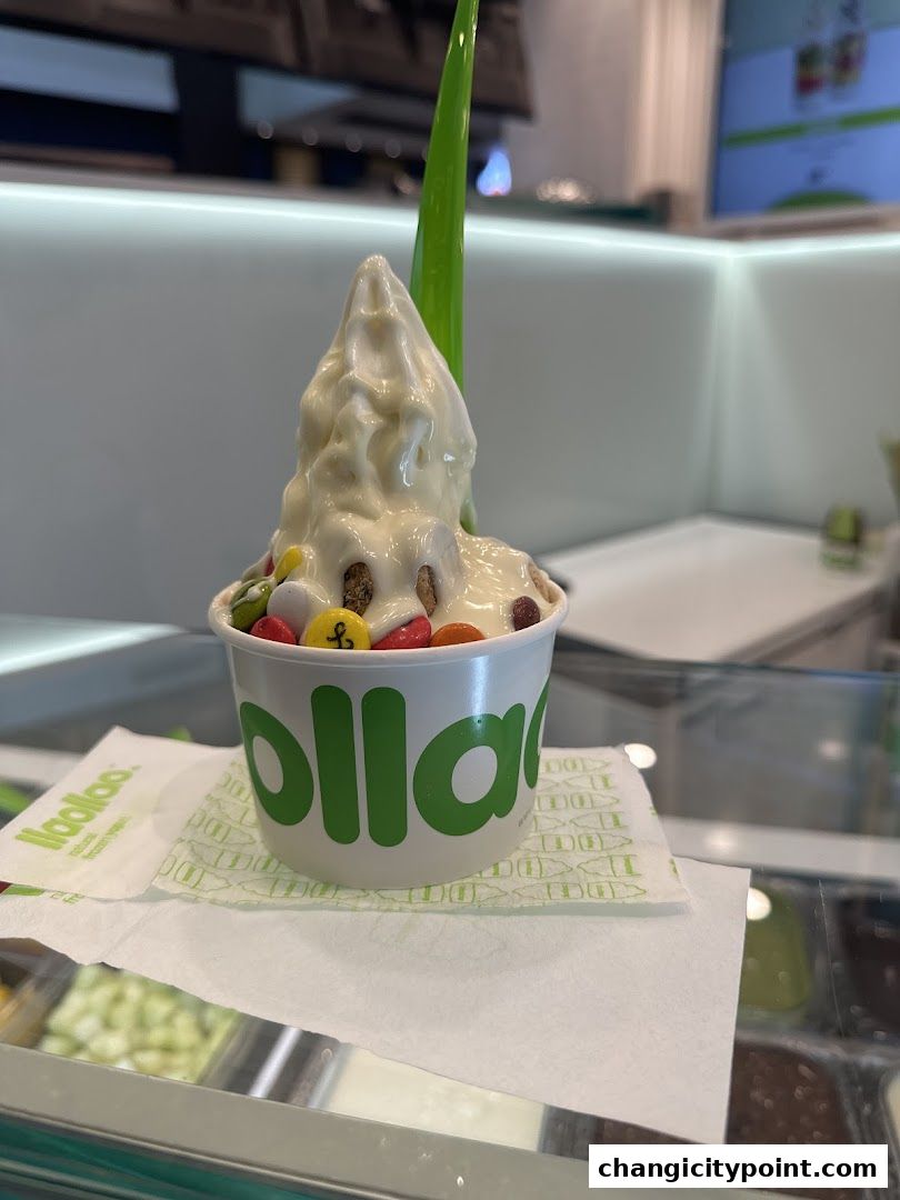 A cup of llaollao frozen yogurt topped with white sauce and colorful candies.