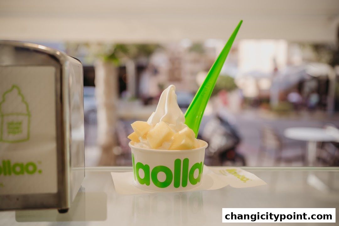 A cup of llaollao frozen yogurt with fruit and a green spoon.