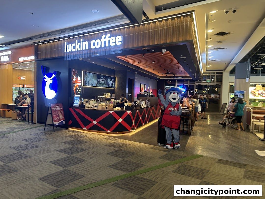 The exterior of a Luckin Coffee shop with a mascot and seating area.