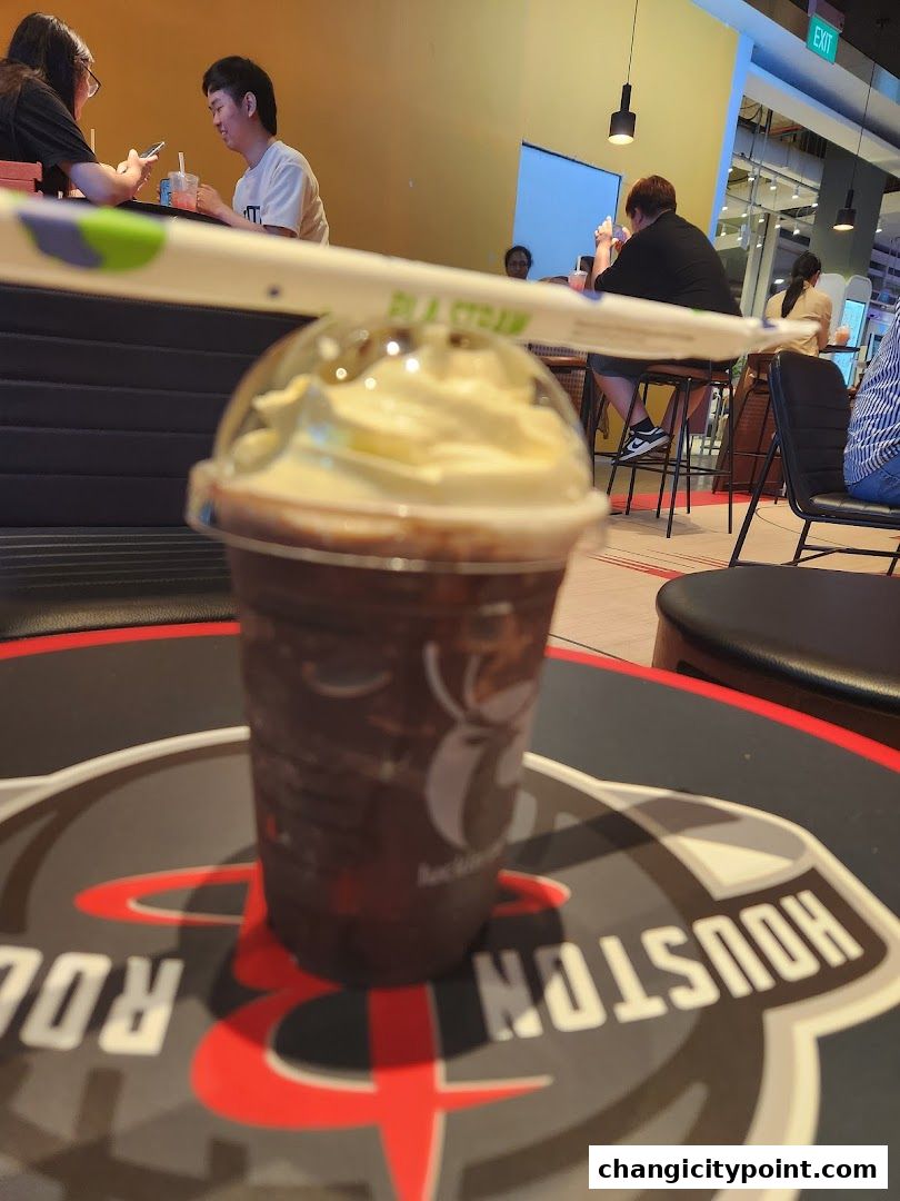 A close-up of a Luckin Coffee drink with people in the background.