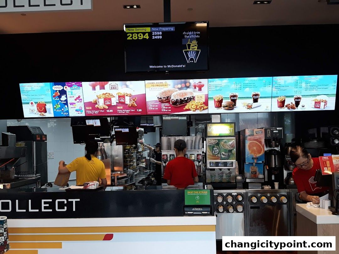 McDonald's counter with digital menu boards displaying food and happy meals.
