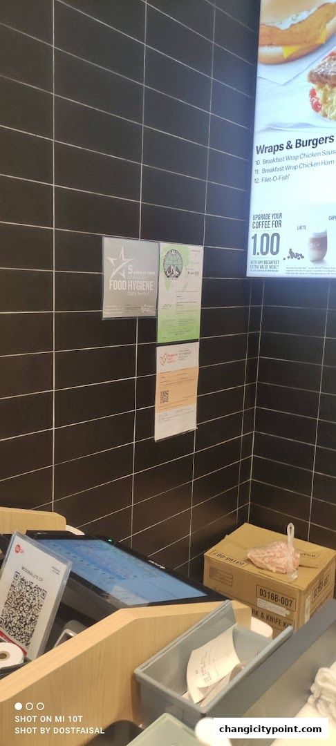 Interior view of a McDonald's counter with a digital menu and hygiene certificates.