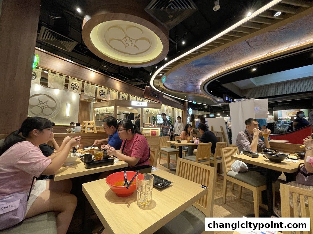 Diners enjoy meals at tables inside a Japanese restaurant with traditional decor.